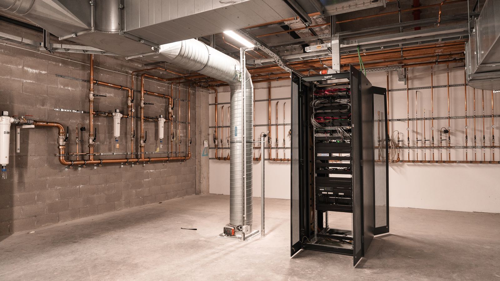 Technical room of an operating theatre before integration, bare concrete, service networks and a standalone rack